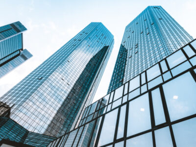 Low wide-angle view looking up to modern skyscrapers in business district on a beautiful sunny day with blue sky and clouds